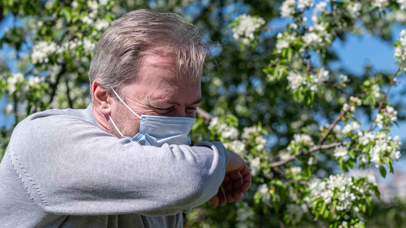 Un hombre tose portando una mascarilla