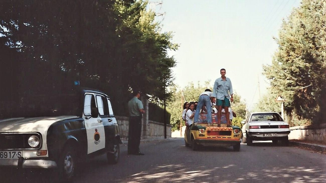 Un guardia civil ante un vehículo con jóvenes y ambiente festivo