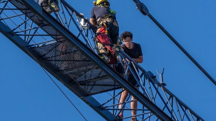 Bomberos de Sevilla acompañan en el descenso a un joven que se había encaramado a una grúa pluma / EUROPA PRESS