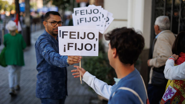 Dos personas sujetan pancartas que aluden al líder del PP, Alberto Núñez Feijóo / EUROPA PRESS