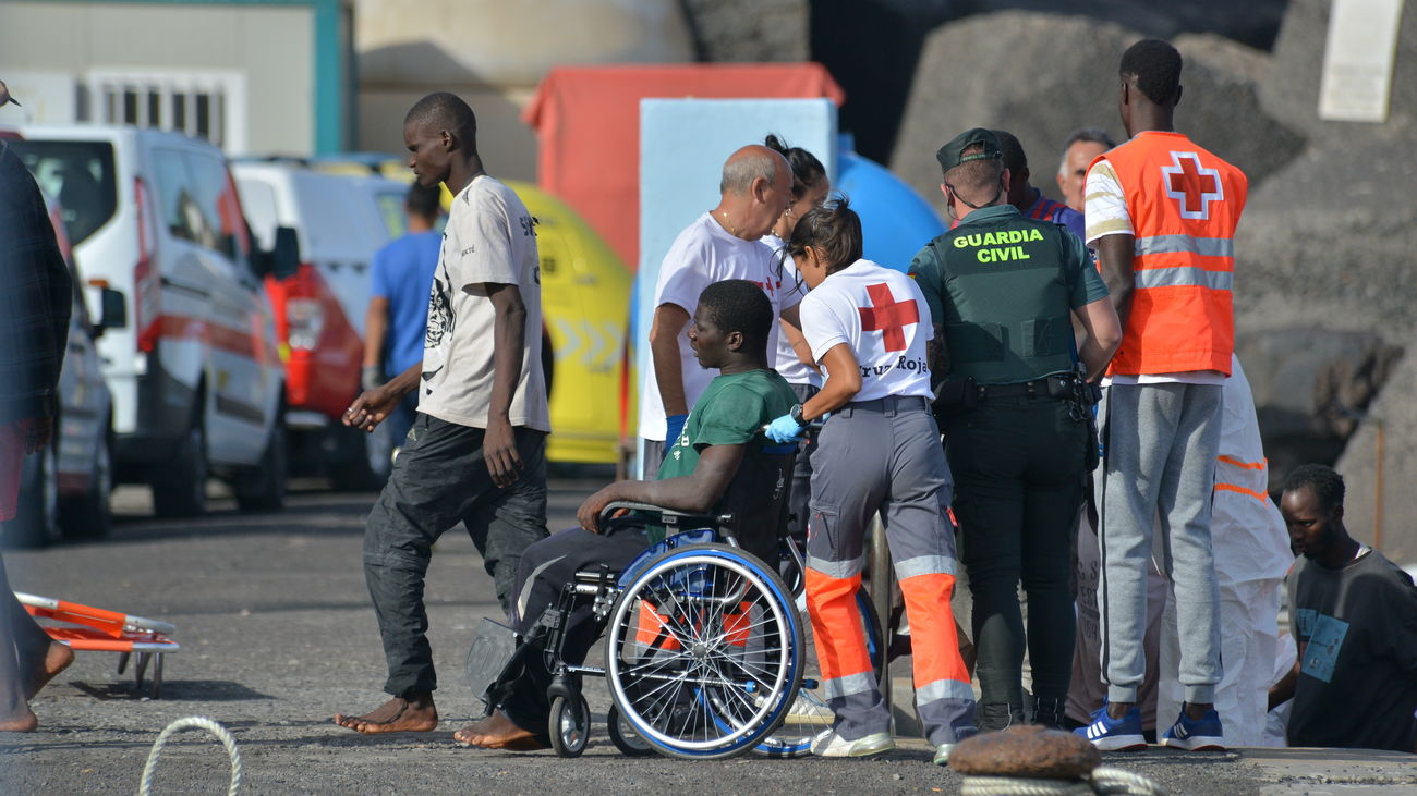 Una trabajadora de la Cruz Roja traslada en silla de ruedas a uno de los migrantes que ha llegado en un cayuco al puerto de La Restinga, a 23 de octubre de 2023, en El Hierro, Santa Cruz de Tenerife, Tenerife, Canarias