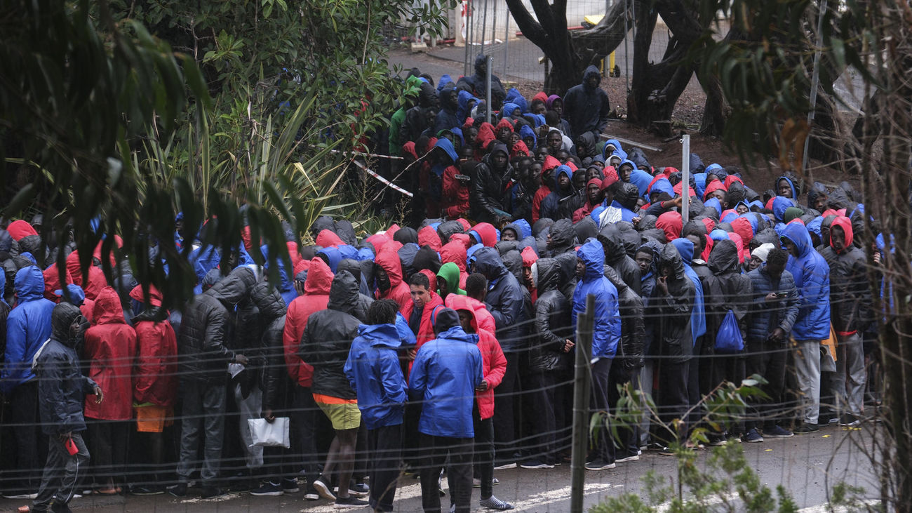 Cientos de migrantes de origen subsahariano, en su mayoría senegaleses, hacen fila bajo la lluvia este domingo para acceder al centro de acogida para migrantes de Las Raíces en Tenerife
