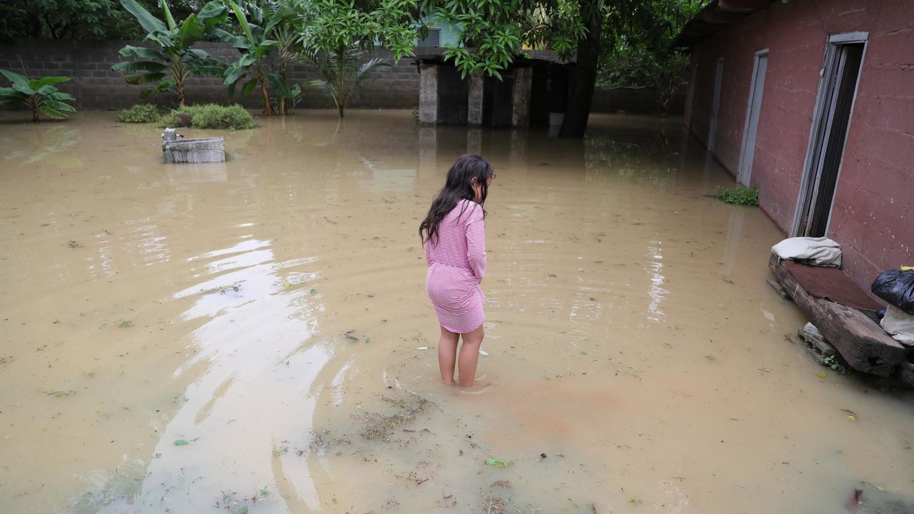 Una niña permanece afuera de su casa inundada hoy, en la ciudad del Progreso (Honduras)