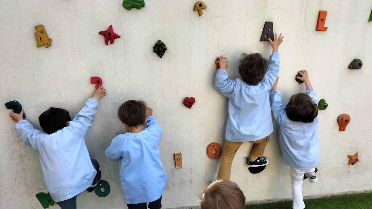 Niños de corta edad juegan a trepar por una pared