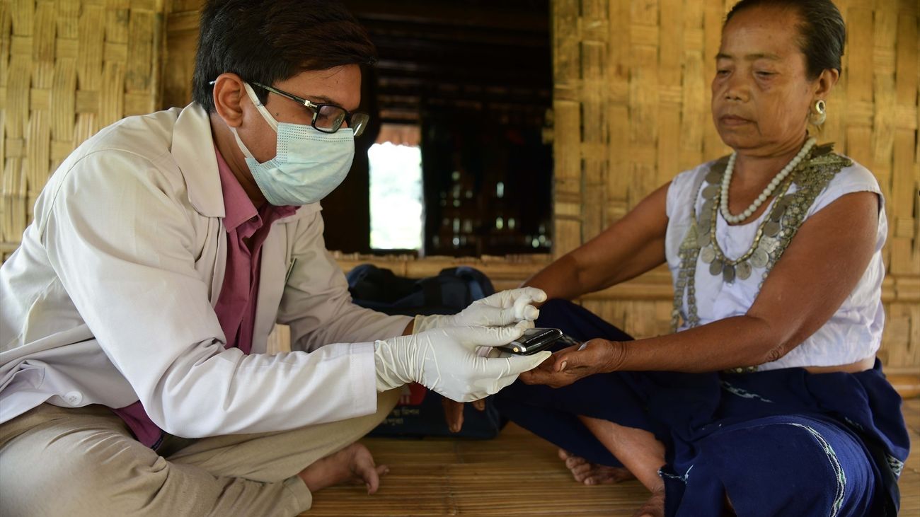Un médico realiza una prueba de malaria a una mujer de la tribu reang en su choza de bambú en el pueblo de Birendranagar