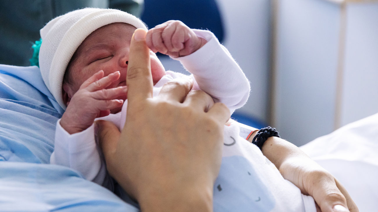 María Liz da un dedo a su hijo Erik, que ha sido el primer bebé nacido en 2024 en Madrid, en el Hospital Universitario La Paz
