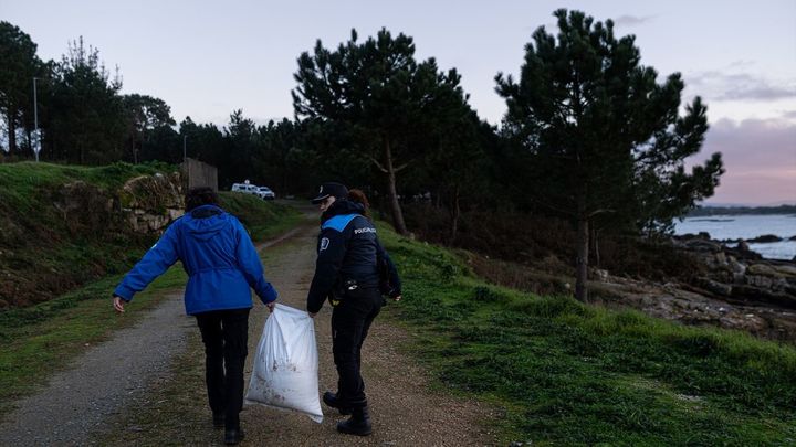 Un agente de la Policía Local y una guarda costas recogen pellets de la arena / Europa Press