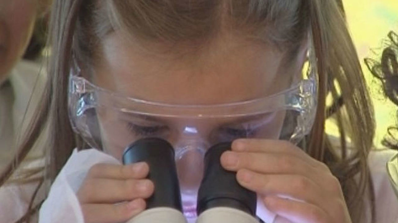 Una niña mira por un microscopio