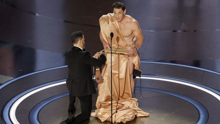 El presentador Jimmy Kimmel (L) ata una bata alrededor de John Cena (R) / EFE