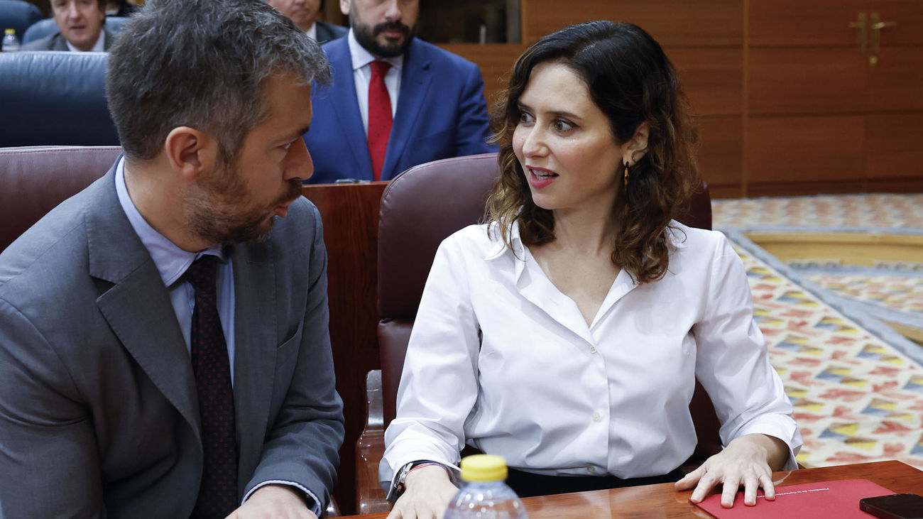 La presidenta de la Comunidad de Madrid, Isabel Díaz Ayuso (d), conversa con el consejero de Presidencia, Justicia y Administración Local, Miguel Ángel García Martín