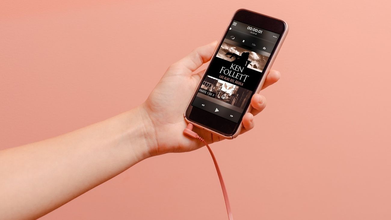 Un usuario sosteniendo un smartphone con el que escucha un audiolibro