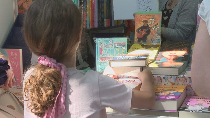 Una niña escoge libros en la Feria del Libro