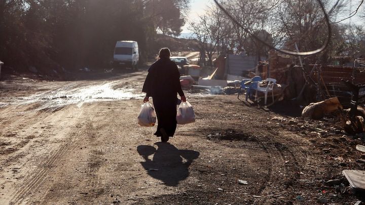 Una mujer camina por la Cañada Real con bolsas que ha recogido en la entrega de regalos y alimentos / EUROPA PRESS