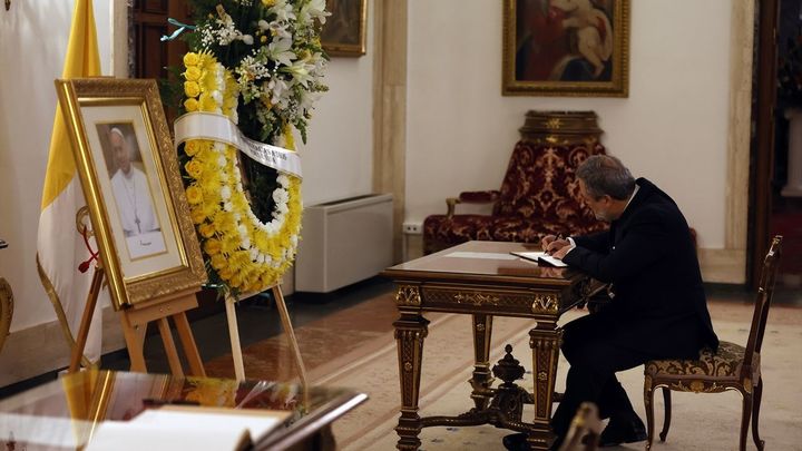 Un hombre firma en un libro de condolencias abierto por el fallecimiento del Papa Francisco I, junto a un retrato del Papa y una corona de flores, en la Nunciatura Apostólica / EUROPA PRESS