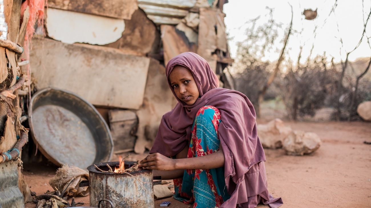 Una joven enciende una cocina de leña en una aldea de Somalia