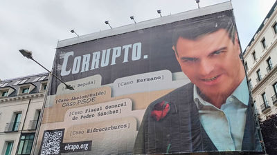 Hazte Oír despliega una lona frente al Congreso con una imagen de Pedro Sánchez acompañado del lema "Corrupto"