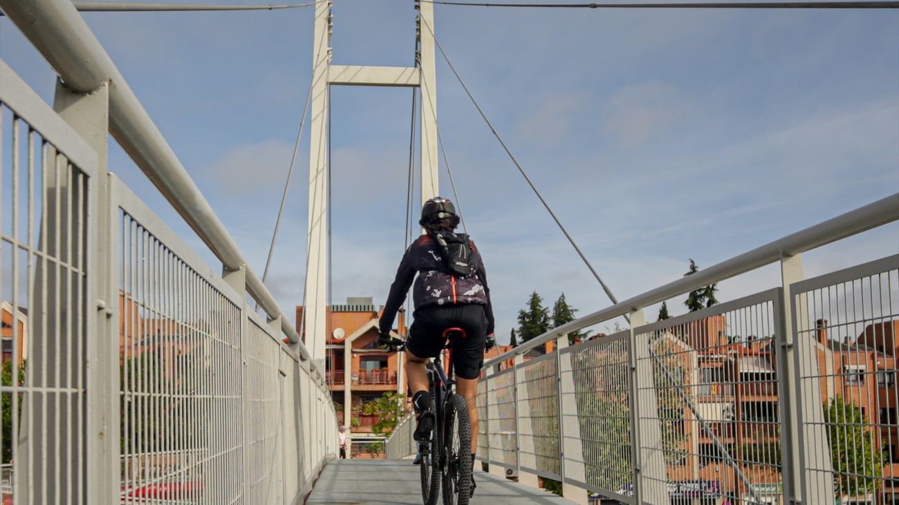 Un hombre circula en bicicleta por una pasarela en Madrid