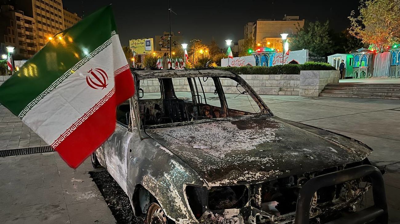 Un coche calcinado con la bandera de Irán, en Teherán