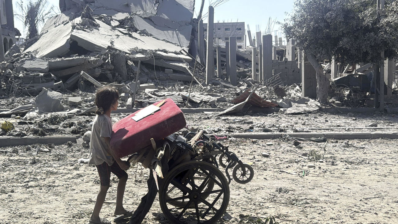 Una niña carga con objetos en una silla de ruedas, en Ciudad de Gaza