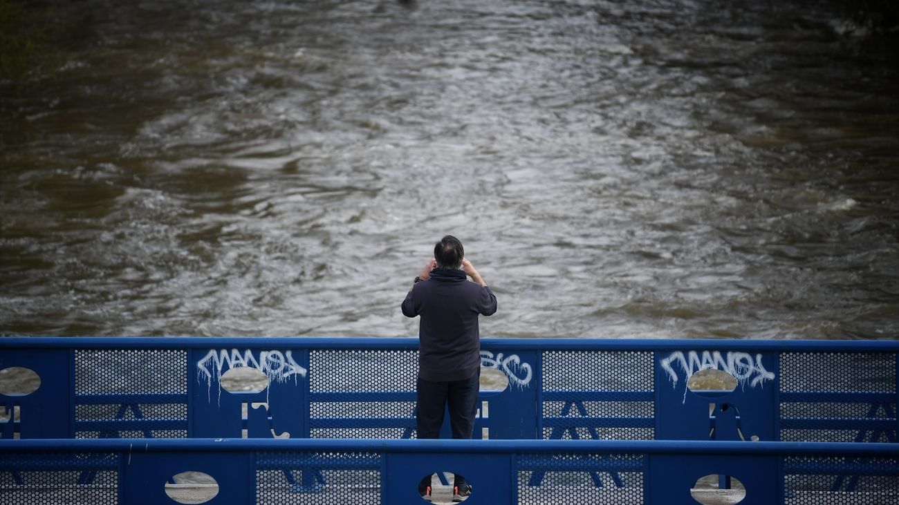 Una persona ante la crecida del río, en el parque lineal del Manzanares