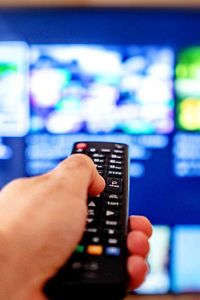 Persona con el mando a distancia delante de la televisión