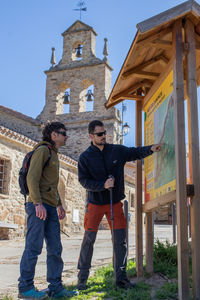 Dos senderistas ante un panel de la red de caminos de la Sierra Norte de Madrid