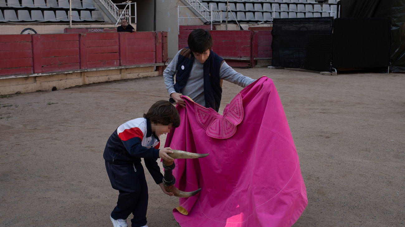 Dos niños juegan con un capote y unos cuernos de toro durante un acto por el Día Internacional de la Tauromaquia, en la Plaza de Toros La Monumental de Barcelona