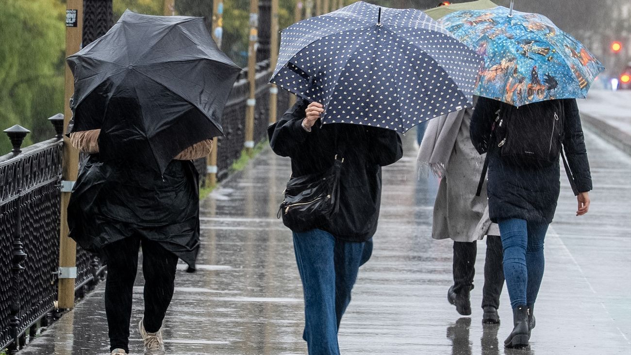 Peatones cruzan el puente de Triana en Sevilla en una jornada marcada por la lluvia y el viento, provocados por el paso de la borrasca Joseph