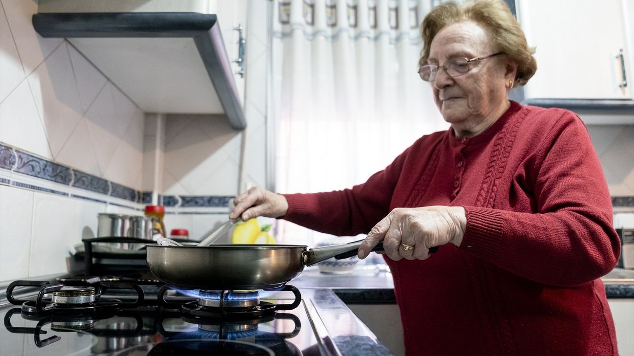 Una mujer prepara comida sobre un fuego de cocina