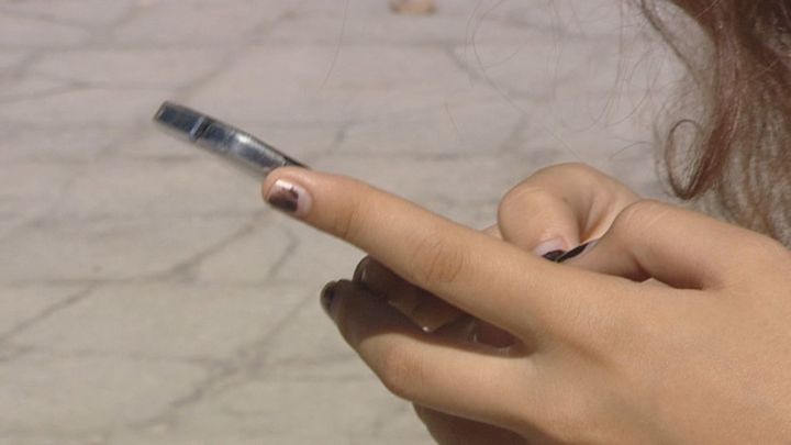 Un menor sostiene teléfono móvil en la mano