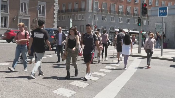 Gente cruzando un paso de cebra con semáforo en Madrid
