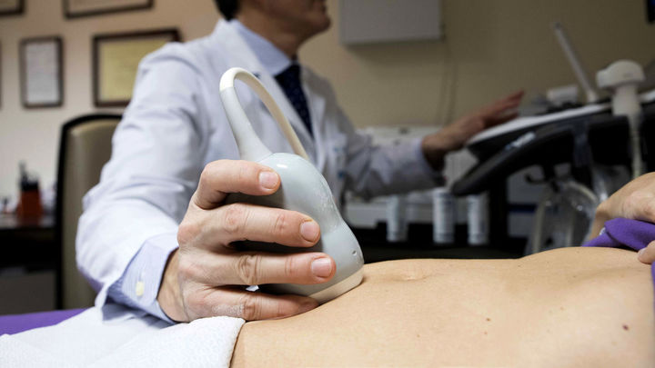 Un médico realiza una ecografía a una paciente embarazada