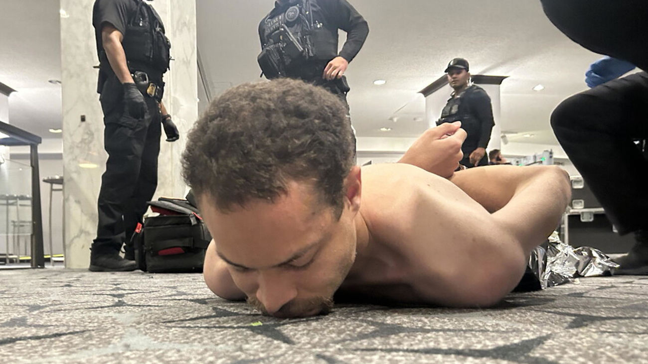 Fotografía difundida en la cuenta oficial @realDonaldTrump de la red social Truth del presidente de los Estados Unidos, Donald Trump, donde se muestra al supuesto tirador arrestado por agentes del Servicio Secreto