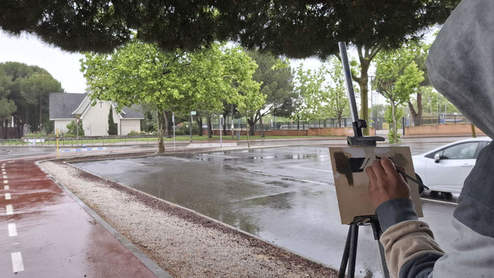 El artista Anderson Romero pinta, bajo la lluvia, un cuadro en Las Rozas / EFE