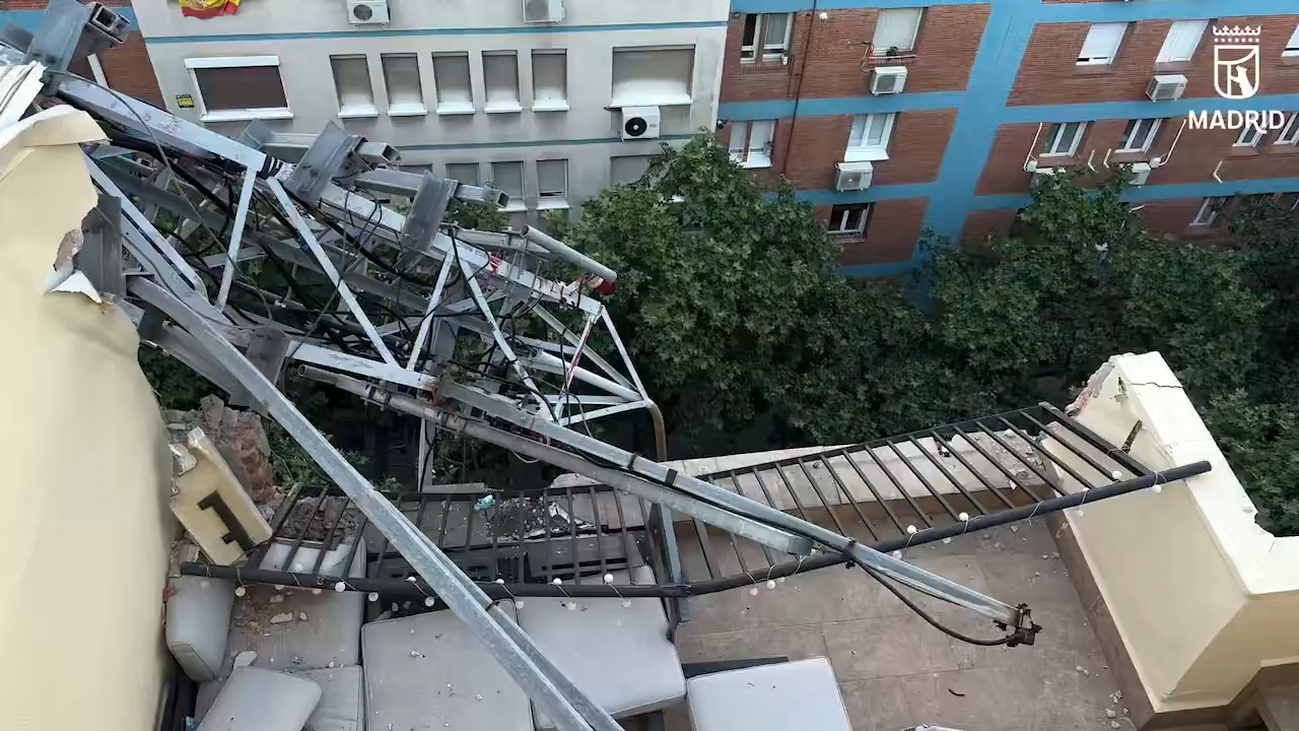 Los bomberos retiran una antena de 20 metros que cayó sobre la cubierta de un edificio en Madrid