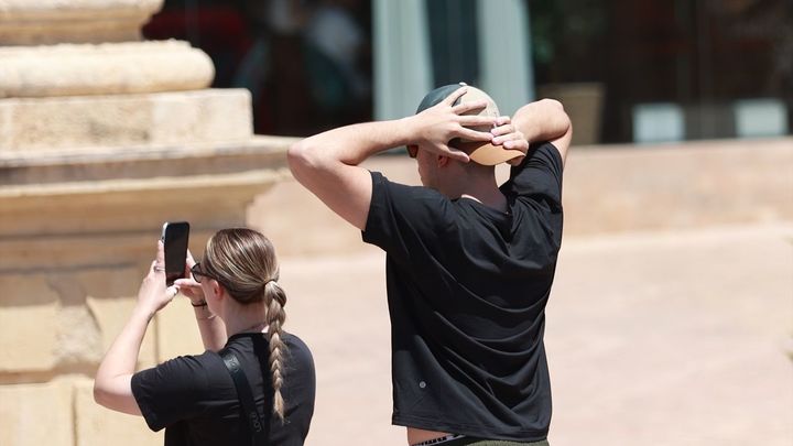 Un ciudadano se protege la cabeza por el calor