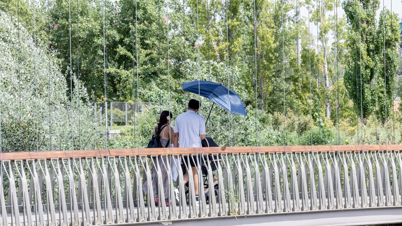 Dos personas se protegen del sol con una sombrilla en Madrid