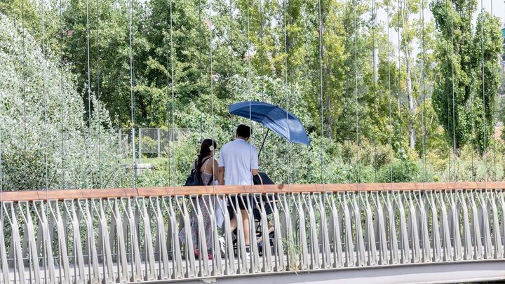 Dos personas se protegen del sol con una sombrilla en Madrid