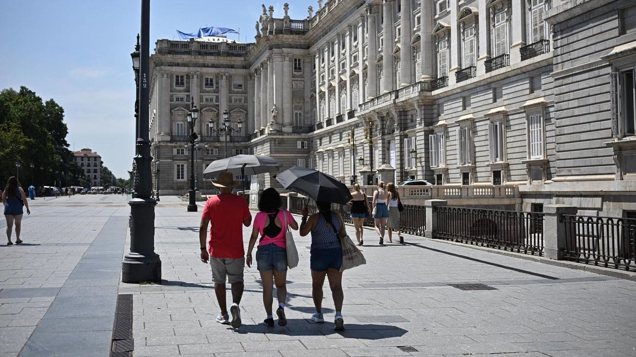 Varias personas se protegen del sol frente al Palacio Real en Madrid
