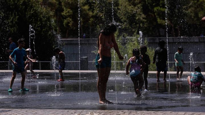 Personas se refrescan en una fuente de Madrid Río