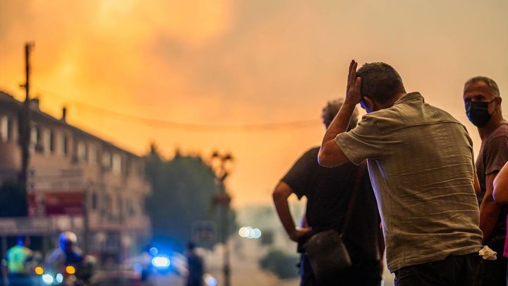 Varias personas observan el fuego durante las labores de extinción del incendio forestal en La Adrada, Ávila