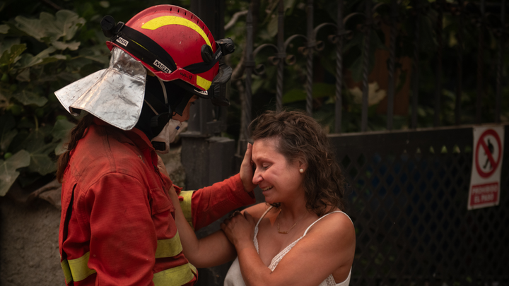 Bombero consuela a una mujer por el incendio de la Sierra Oeste