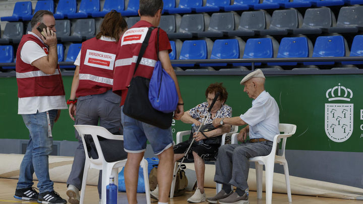 Miembros de Emergencia Social de la Comunidad de Madrid conversan con una pareja de evacuados por el incendio / EFE