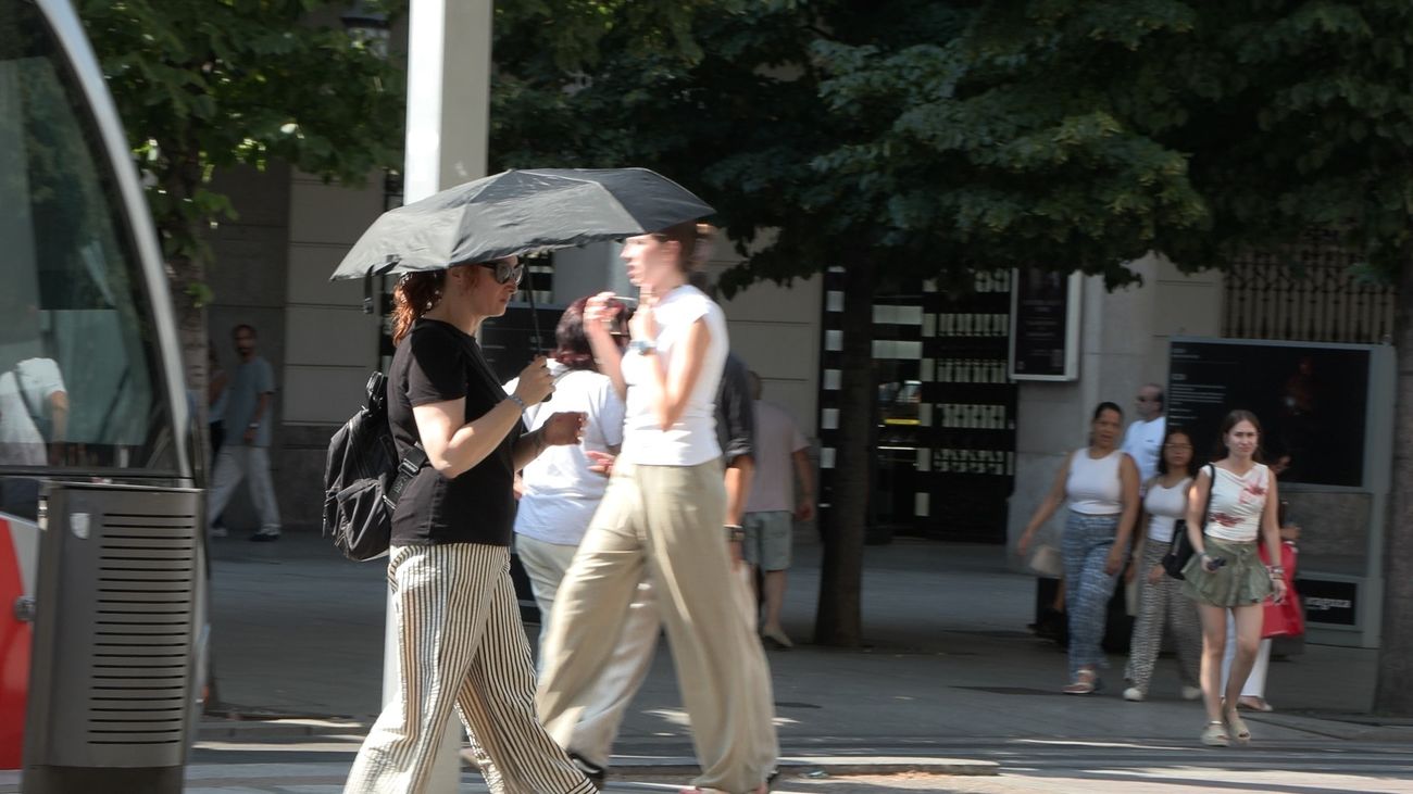Una persona se protege del calor por las calles de Madrid