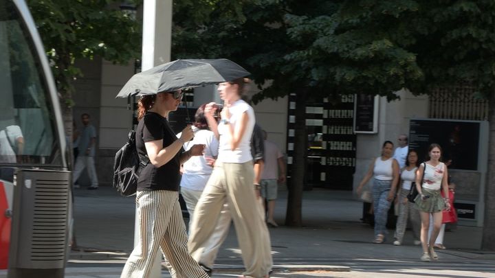 Una persona se protege del calor por las calles de Madrid