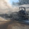 Un bombero refresca un autobús calcinado
