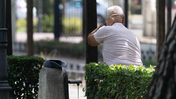 Una persona se refresca en una fuente en Madrid