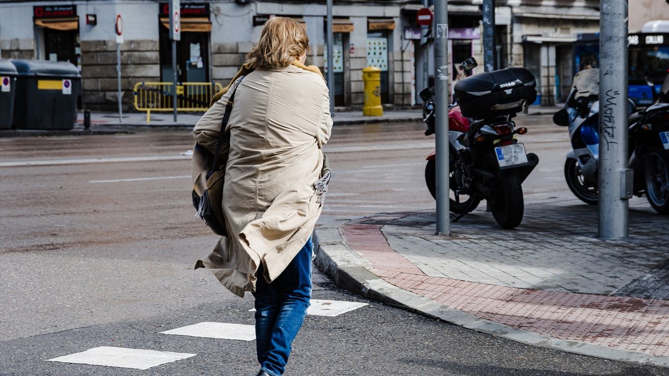 Una mujer cruza una calle de Madrid con viento